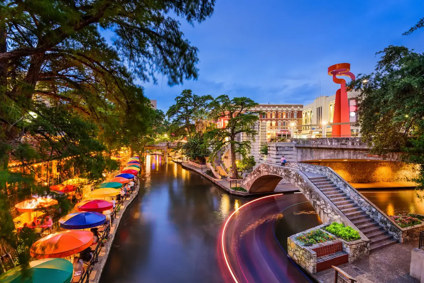 Colorful image of Texas riverwalk with colorful umbrellas and stone bridges and walkways